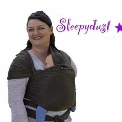 white woman wearing a baby in The Sleepydust Wrap Soft Moss with a whit background and the Sleepydust logo